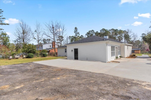 rear view of house featuring concrete driveway and fence