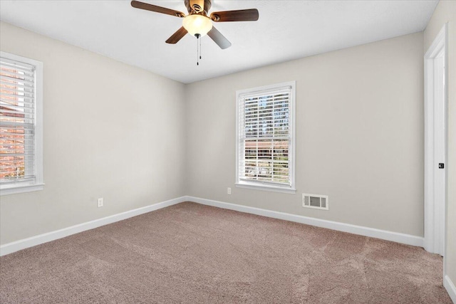 carpeted empty room featuring baseboards, visible vents, and ceiling fan