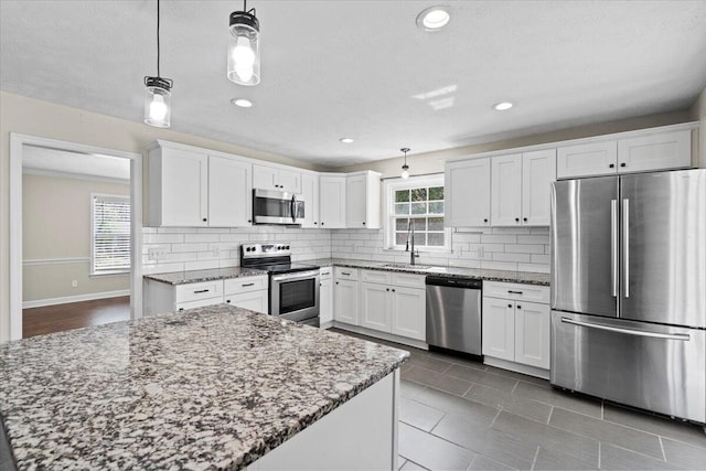 kitchen featuring tasteful backsplash, pendant lighting, appliances with stainless steel finishes, and white cabinetry