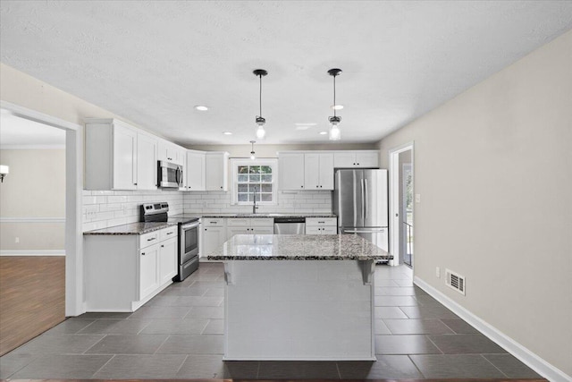 kitchen with stainless steel appliances, tasteful backsplash, and white cabinets