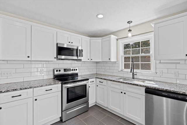 kitchen with a sink, tasteful backsplash, white cabinetry, stainless steel appliances, and light stone countertops