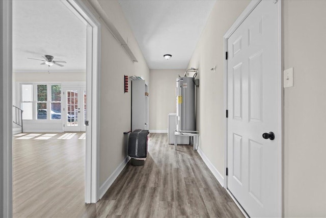 hallway with water heater, baseboards, and wood finished floors