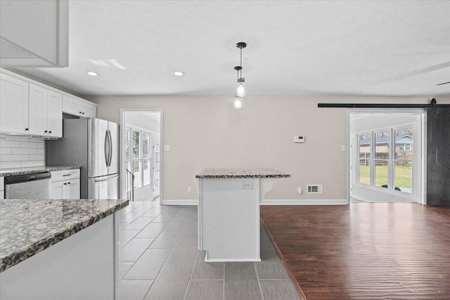 kitchen with dark stone countertops, visible vents, appliances with stainless steel finishes, white cabinetry, and tasteful backsplash