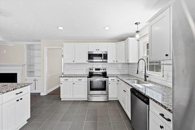 kitchen with a sink, tasteful backsplash, appliances with stainless steel finishes, white cabinets, and light stone countertops