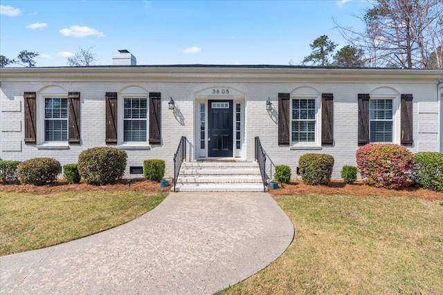 view of front facade featuring crawl space, brick siding, a chimney, and a front lawn