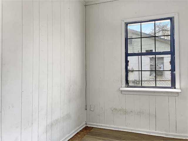 empty room with wooden walls and dark hardwood / wood-style flooring