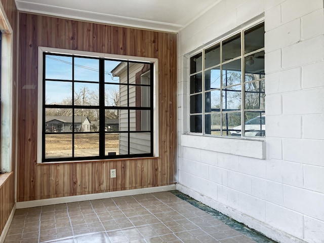 interior space featuring a healthy amount of sunlight, wooden walls, and tile patterned floors