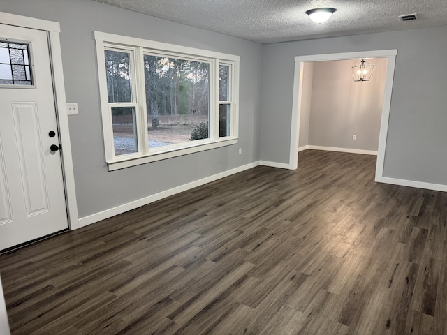 interior space featuring visible vents, a textured ceiling, baseboards, and dark wood-type flooring