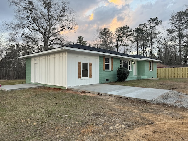 single story home featuring concrete driveway, brick siding, fence, and a front lawn