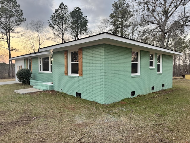 view of property exterior with crawl space, brick siding, and a lawn