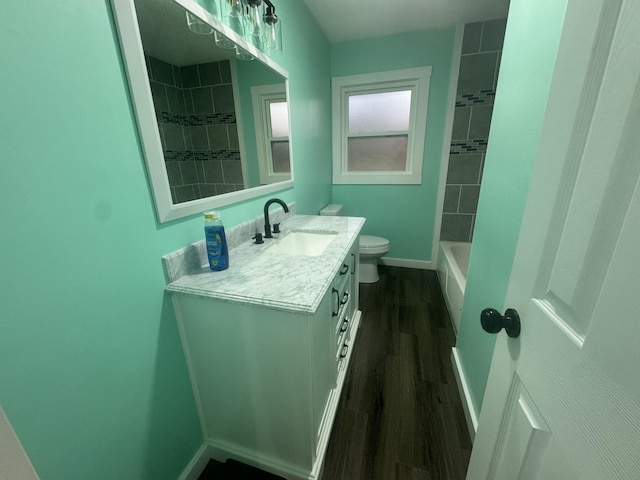 bathroom with baseboards, toilet, shower / tub combination, wood finished floors, and vanity