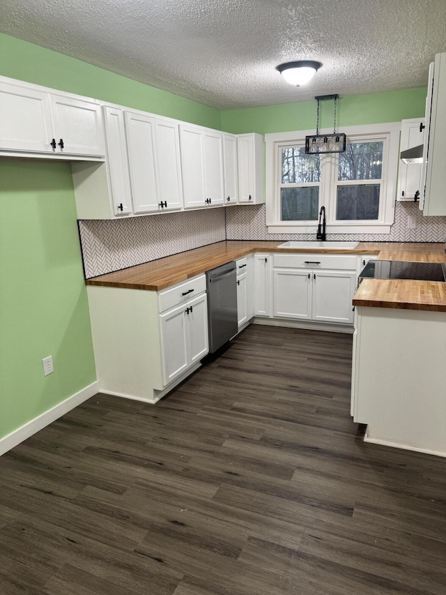 kitchen featuring stainless steel dishwasher, white cabinetry, wooden counters, and a sink