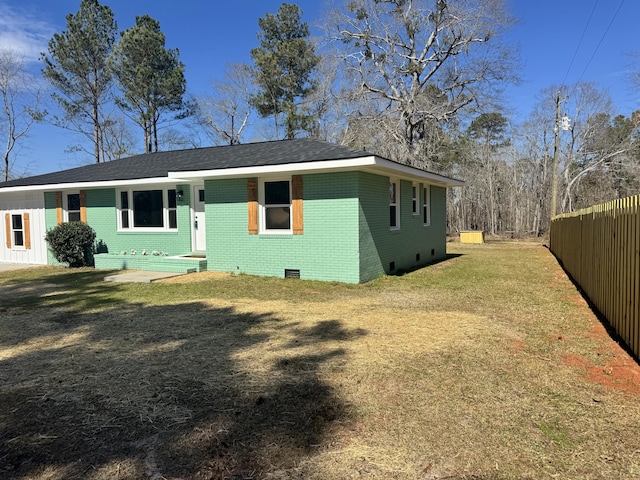 exterior space with crawl space, a yard, fence, and brick siding