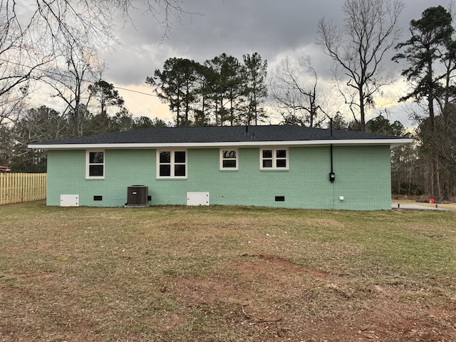 back of house with crawl space, a lawn, and central AC unit