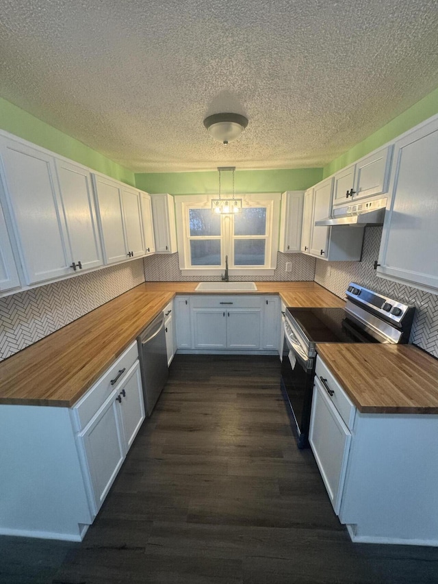 kitchen with butcher block countertops, appliances with stainless steel finishes, white cabinetry, and under cabinet range hood