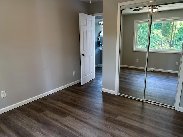 unfurnished bedroom featuring a closet, dark wood-type flooring, and ceiling fan