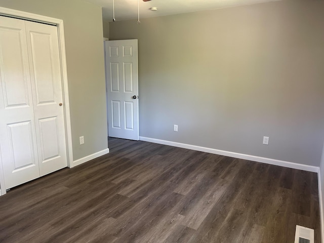 unfurnished bedroom with dark hardwood / wood-style flooring and a closet