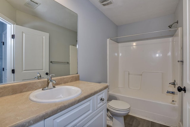 full bathroom with vanity, hardwood / wood-style flooring, toilet, and  shower combination