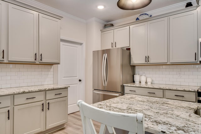 kitchen featuring ornamental molding, light wood-style flooring, freestanding refrigerator, and backsplash