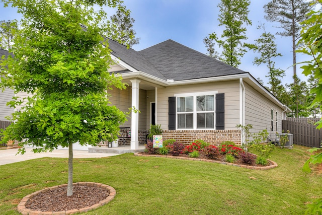 view of front of property featuring brick siding, fence, a front lawn, and central AC unit