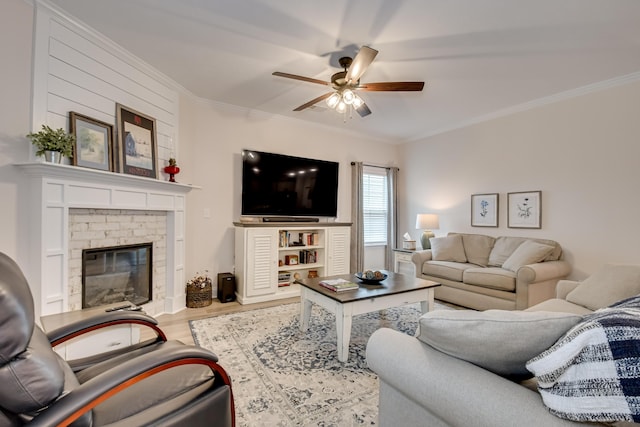 living room with wood finished floors, a ceiling fan, crown molding, and a brick fireplace