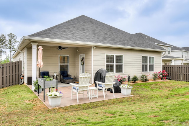 back of property featuring a patio, ceiling fan, a fenced backyard, and a lawn