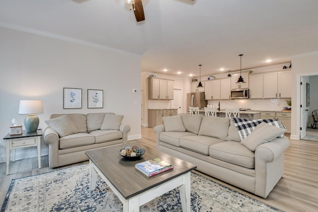living area with recessed lighting, ceiling fan, light wood-type flooring, crown molding, and baseboards