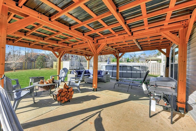 view of patio with a trampoline and an outdoor living space with a fire pit