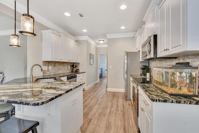 kitchen featuring appliances with stainless steel finishes, decorative light fixtures, white cabinetry, dark stone countertops, and kitchen peninsula