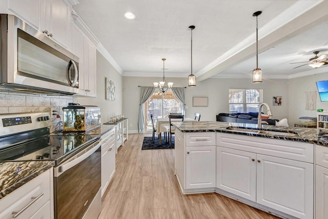 kitchen featuring sink, white cabinetry, hanging light fixtures, dark stone countertops, and stainless steel appliances