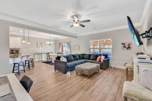 living room with ceiling fan with notable chandelier, light hardwood / wood-style flooring, and ornamental molding