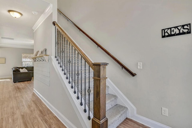 stairs featuring hardwood / wood-style flooring and ornamental molding