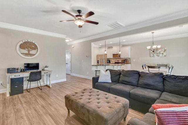 living room with ceiling fan with notable chandelier, ornamental molding, and light hardwood / wood-style floors