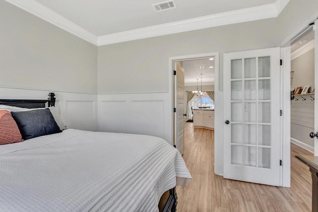 bedroom featuring light hardwood / wood-style flooring, ornamental molding, and a chandelier