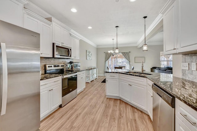 kitchen with white cabinetry, stainless steel appliances, decorative light fixtures, and sink