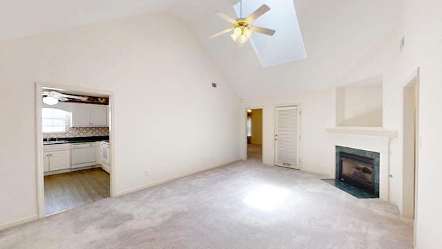 431 Connemara Trl, Evans, GA 30809 - unfurnished living room featuring ceiling fan, high vaulted ceiling, light colored carpet, a fireplace with flush hearth, and a skylight