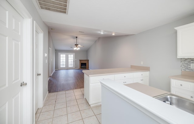 kitchen with light tile patterned flooring, a center island, decorative backsplash, and white cabinets