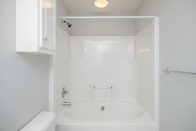 bathroom with washtub / shower combination and toilet