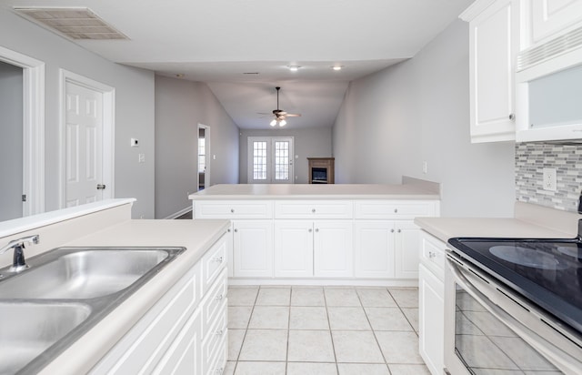 kitchen with sink, ceiling fan, tasteful backsplash, white cabinets, and stainless steel range with electric cooktop