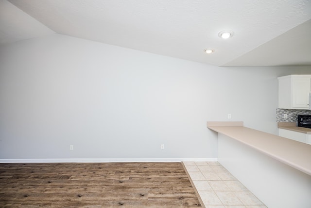 tiled spare room with lofted ceiling