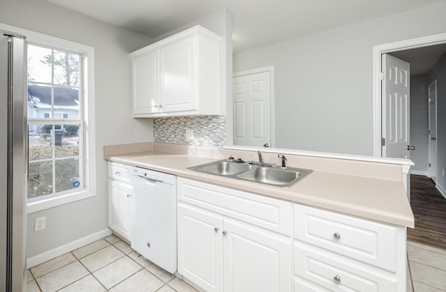 kitchen with white cabinetry, dishwasher, sink, decorative backsplash, and kitchen peninsula