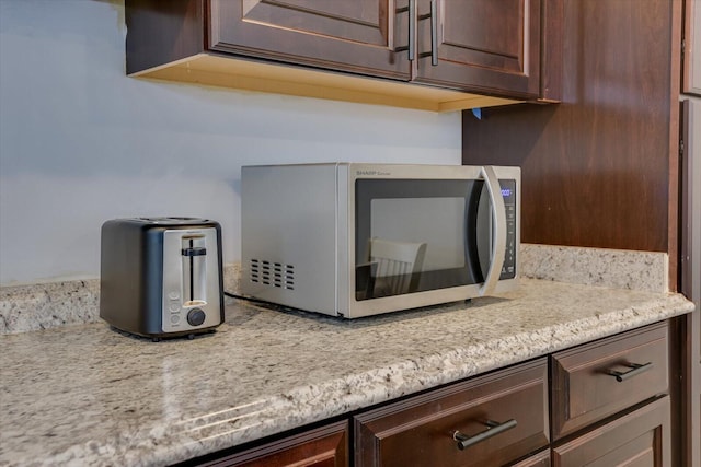 interior details featuring light stone countertops and dark brown cabinetry