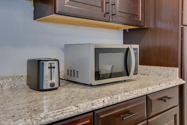 interior details featuring light stone countertops and dark brown cabinetry