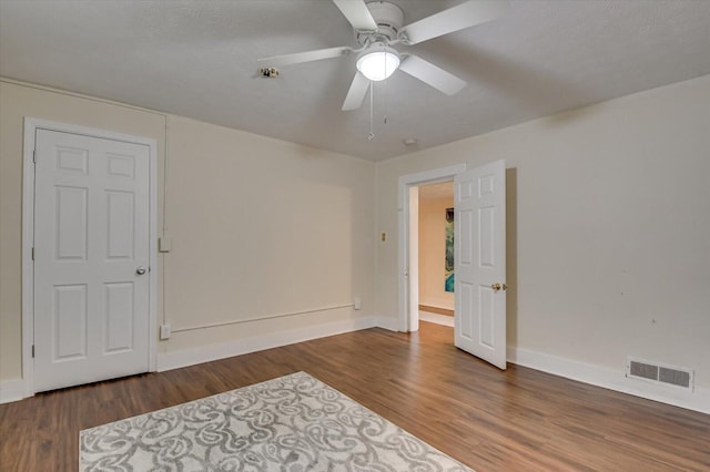 unfurnished room with a textured ceiling, ceiling fan, and dark wood-type flooring