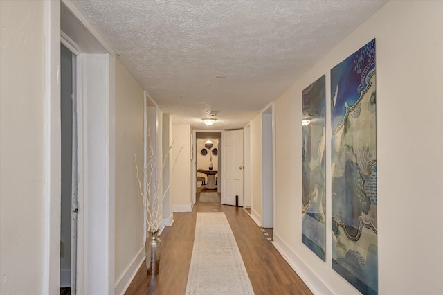 hallway featuring wood-type flooring and a textured ceiling