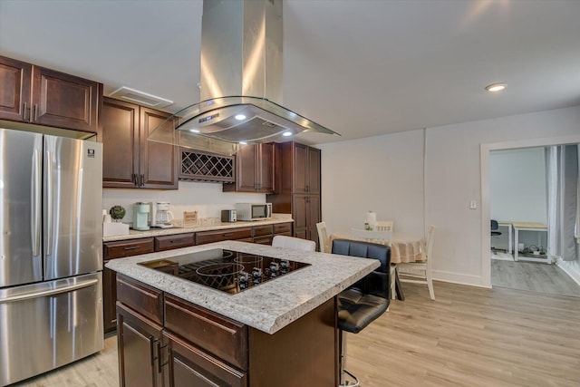 kitchen featuring a center island, stainless steel appliances, a kitchen bar, island range hood, and light wood-type flooring