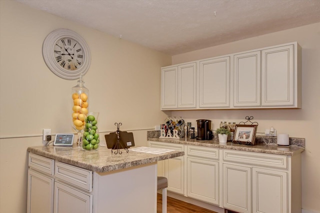 kitchen featuring hardwood / wood-style flooring, pendant lighting, light stone counters, and kitchen peninsula