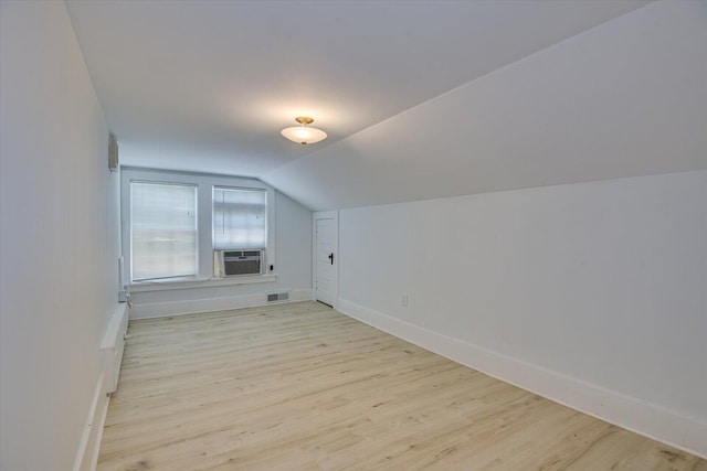 additional living space featuring light hardwood / wood-style floors, vaulted ceiling, and cooling unit