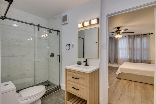 bathroom featuring ceiling fan, vanity, a shower with shower door, and toilet