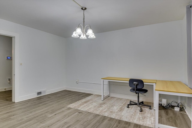 office space featuring built in desk, wood-type flooring, and a chandelier